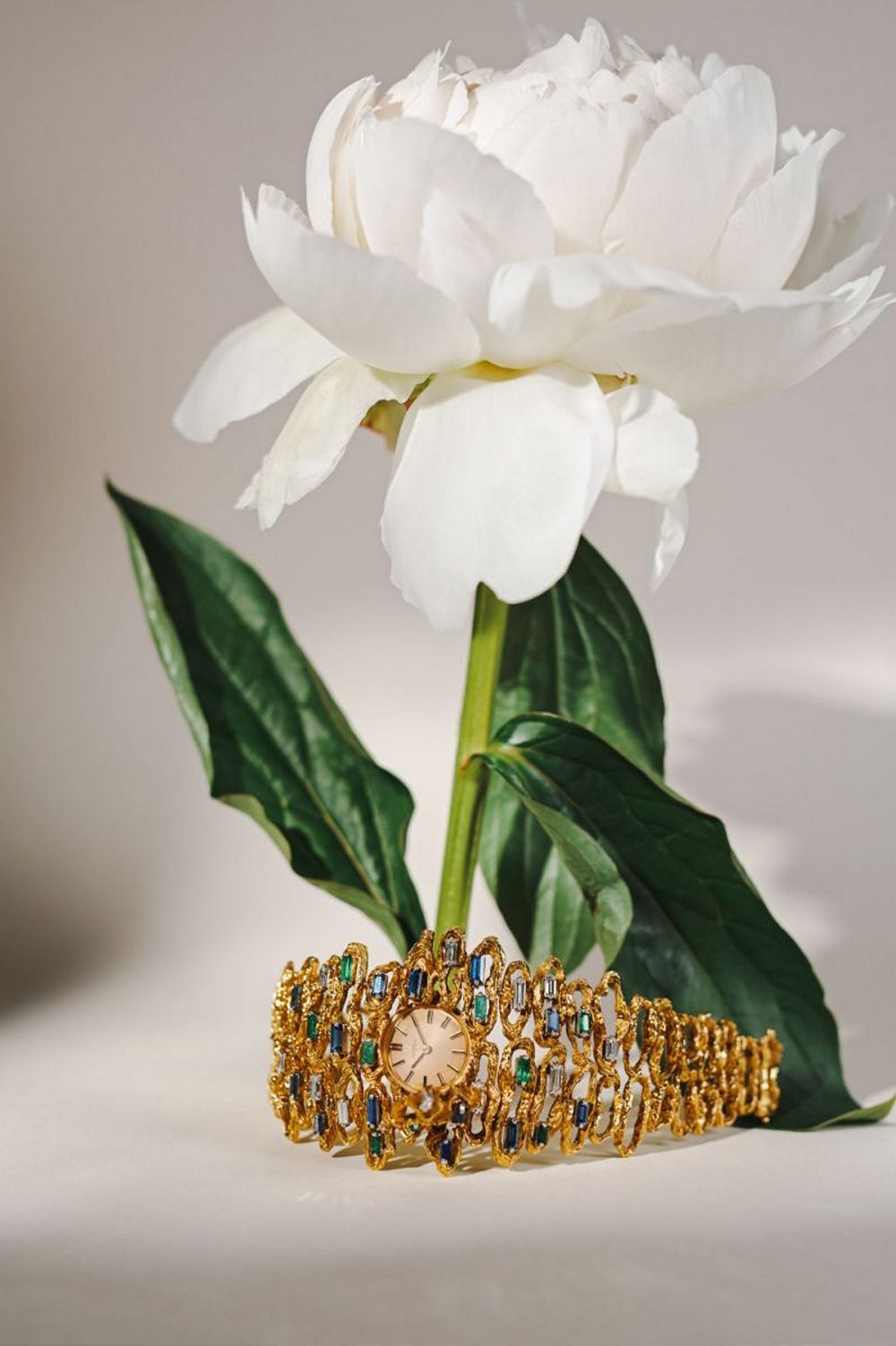 Часы-манжета Omega Jewellery in Secret из желтого золота 750 пробы с бриллиантами, сапфирами и изумрудами, около 1964 года