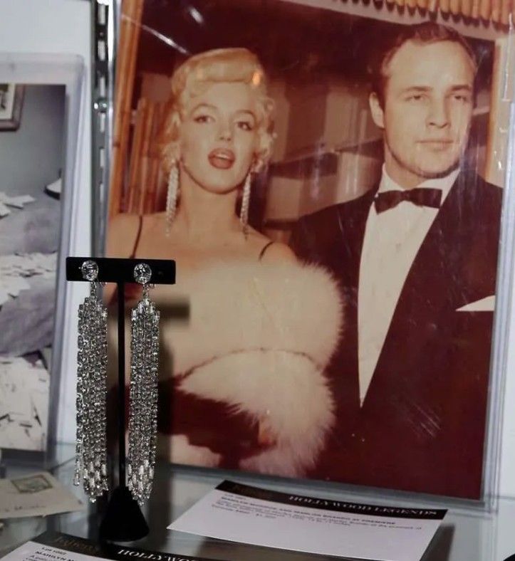 Серьги Мэрилин Монро на фоне фотографии Монро с Марлоном Брандо (Фото Дэвида Ливингстона /Getty Images)