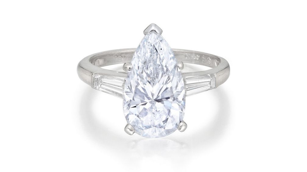 Кольцо с голубым бриллиантом, украшенное двумя коническими бриллиантами багетной огранки и подписью «Cartier London» Кольцо с голубым бриллиантом, украшенное двумя коническими бриллиантами багетной огранки и подписью «Cartier London»