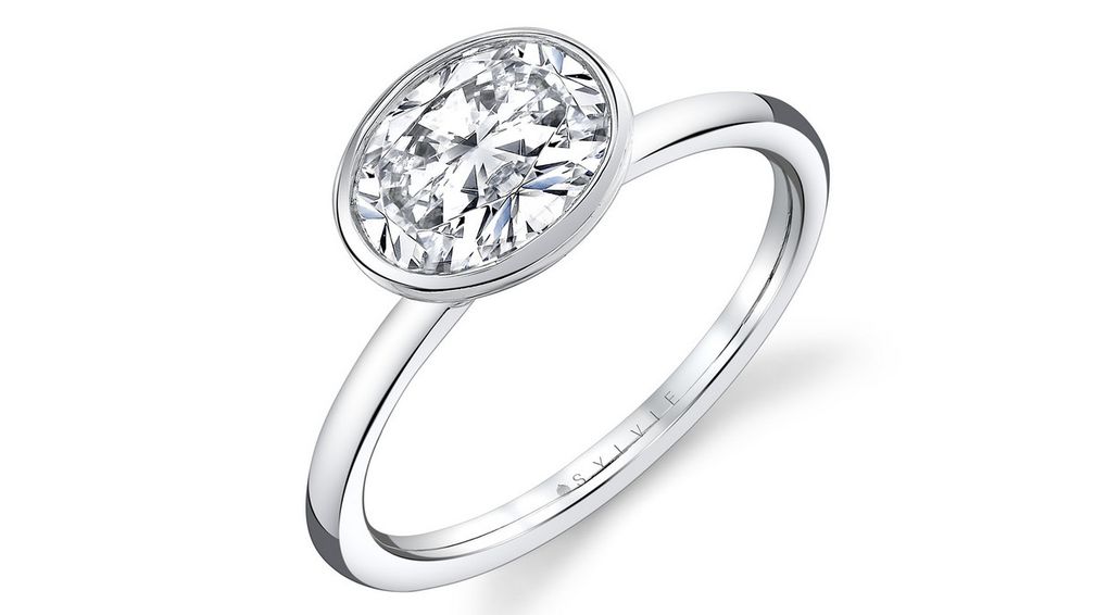 Кольцо Cliodhna от Sylvie Jewelry из 14-каратного белого золота демонстрирует бриллиант овальной огранки в закрепке безель Кольцо Cliodhna от Sylvie Jewelry из 14-каратного белого золота демонстрирует бриллиант овальной огранки в закрепке безель