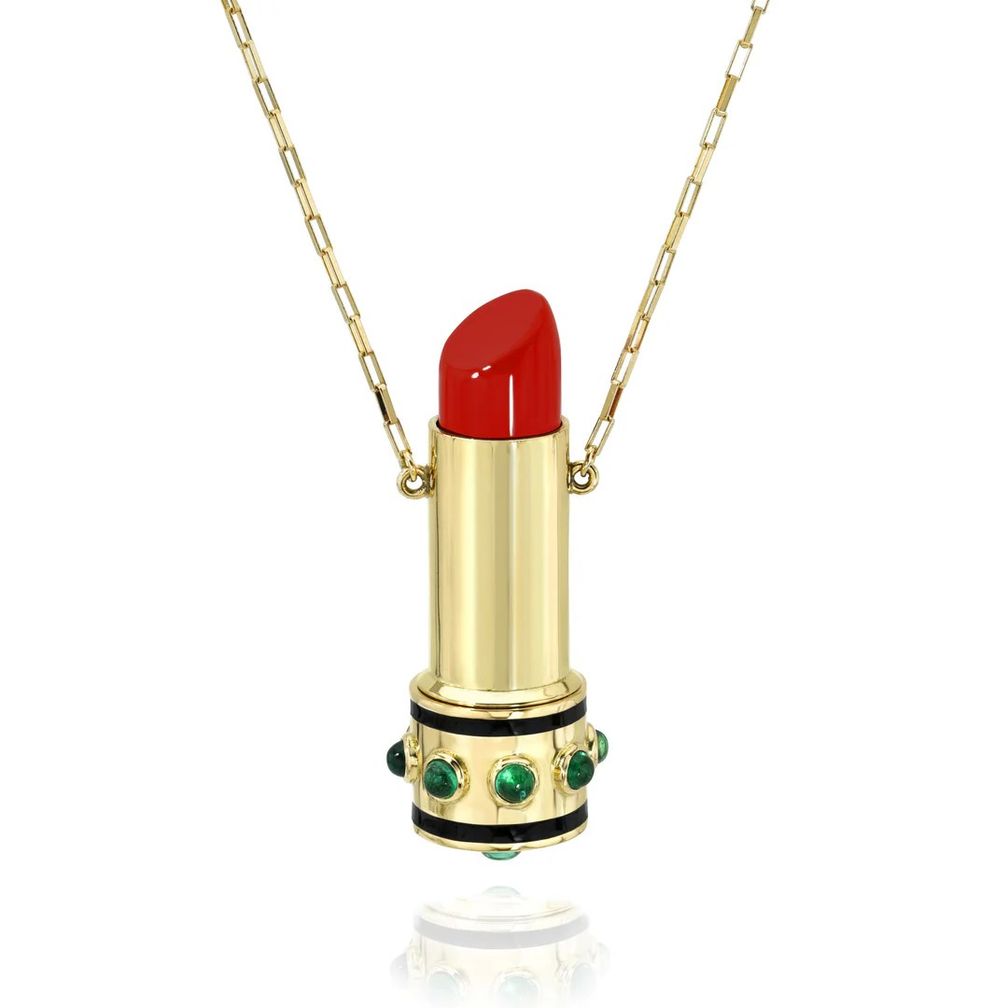 Ожерелье Lipstick Locket из 18-каратного желтого золота имеет подвеску в форме тюбика помады с вырезанным вручную выращенным в лаборатории кораллом. Нижняя часть, украшенная изумрудами Gemfields огранки кабошон и черной эмалевой инкрустацией, откручивается, открывая секретную камеру для памятного подарка