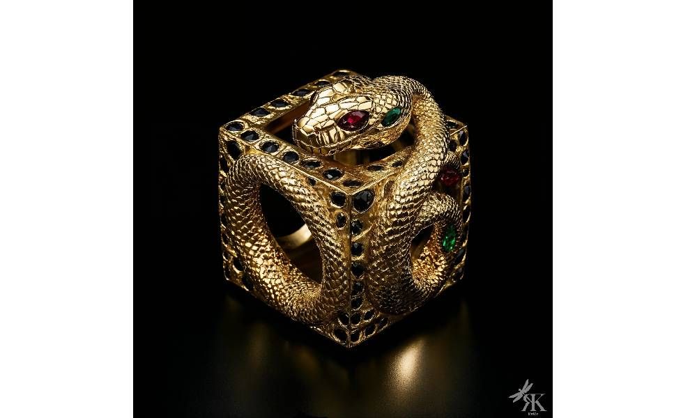 Кольцо из коллекции Kubist под названием Serpent of Fortune выполнено в виде идеального трехмерного куба из полированного желтого золота. На каждой грани выгравированы замысловатые змеиные чешуйки, создающие мерцающий текстурированный эффект. Верхняя грань демонстрирует золотую скульптурную змею. Ее извилистое тело изящно свернуто, инкрустировано рубинами, изумрудами и черными бриллиантами, имитирующими естественные отметины змеи. Глаза змеи — два ярких рубина