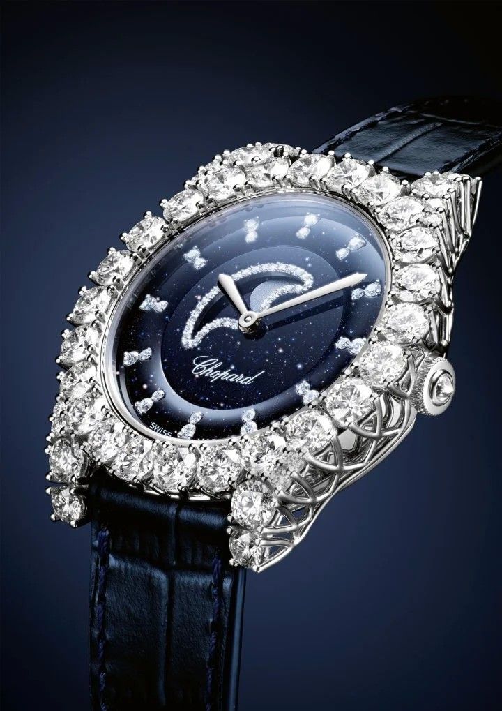 Часы L’Heure du Diamant Moonphase с первым в коллекции усложнением. Новый механизм Chopard 09.02C с автоматическим заводом отображает фазы луны, запас хода 42 часа. Корпус из 18-каратного белого золота (35,75 мм), циферблат из темно-синего авантюрина. Заводная головка из этичного 18-каратного белого золота с бриллиантом огранки бриолет. Безель и ушки из этичного белого золота 18 карат с бриллиантами круглой огранки (3,86 карата). Оправа в виде короны усиливает блеск камней, максимально увеличивая проникновение света. Разработанные Карлом Шойфеле, V-образные зубцы этой оправы поддерживают бриллианты как невидимая кружевная основа
