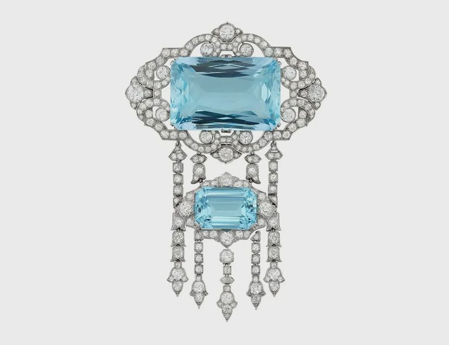 На леди Эдит красуется эта эффектная брошь в стиле позднего ар-деко от Hennell с аквамарином радиантной огранки весом 66,02 карата, обрамленным ромбовидной окантовкой с бриллиантами. К броши подвешена дополнительная деталь, украшенная аквамарином изумрудной огранки и цветочными каплями из пяти бриллиантов в платиновой оправе. Изделие включает в себя съемные элементы и кольцевую застежку, позволяющую превратить брошь в кольцо. Фото: Bentley & Skinner