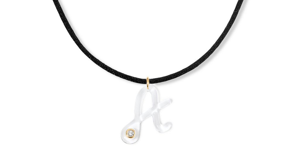 Колье с буквой «A» из эпоксидной смолы Claire, в которую вставлен выращенный в лаборатории бриллиант 0,13 карата, оправленный в 14-каратное желтое золото. Буква нанизана на черный шелковый шнур