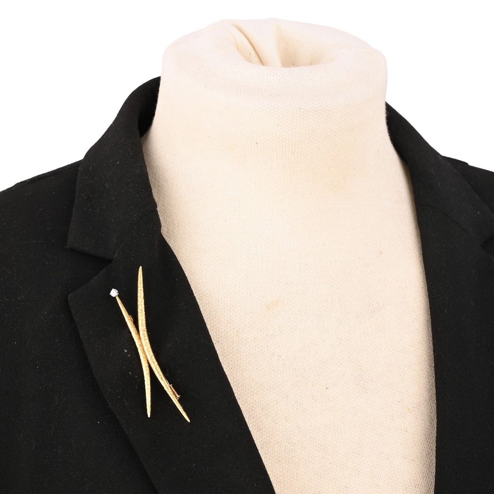 Брошь JK от Эндрю Грима выполнена из фирменного текстурированного 18-каратного желтого золота. Буква J украшена бриллиантом круглой огранки Брошь JK от Эндрю Грима выполнена из фирменного текстурированного 18-каратного желтого золота. Буква J украшена бриллиантом круглой огранки. Фото: Woolley & Wallis