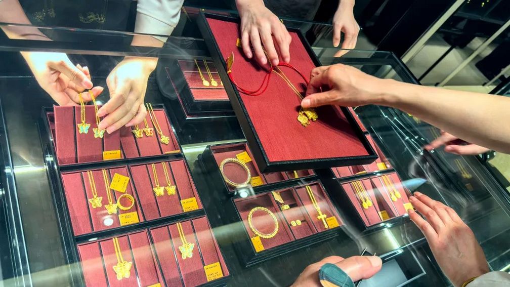 Сотрудники демонстрируют золотые ожерелья покупателям в ювелирном магазине Laopu Gold в Шанхае