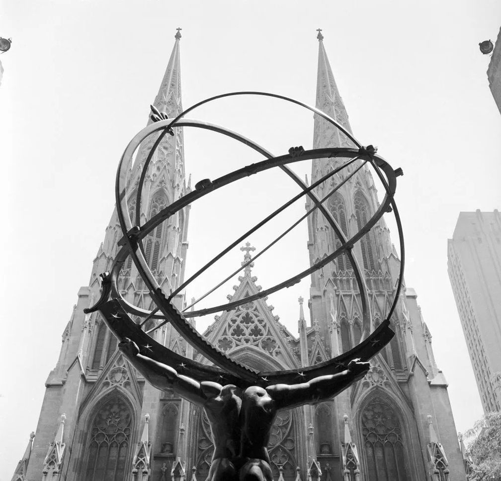 Шпили собора Святого Патрика устремляются в небо над фигурой Атласа, держащего земной шар, в Рокфеллер-центре в Нью-Йорке. Фото: Bettman / Getty Images