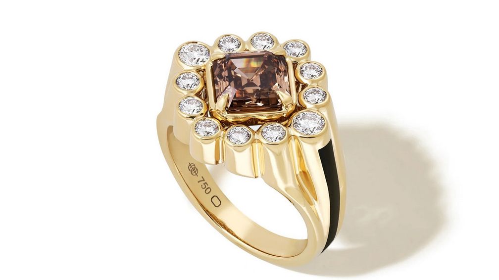 Центральным элементом кольца Sanssouci Bloom стал бриллиант цвета виски (Whiskey Diamond) весом 2,03 карата огранки «Ашер», окруженный белыми бриллиантами (0,74 карата) в глухой закрепке; изделие выполнено из желтого золота 18 карат и декорировано полосой угольно-черной эмали Центральным элементом кольца Sanssouci Bloom стал бриллиант цвета виски (Whiskey Diamond) весом 2,03 карата огранки «Ашер», окруженный белыми бриллиантами (0,74 карата) в глухой закрепке; изделие выполнено из желтого золота 18 карат и декорировано полосой угольно-черной эмали
